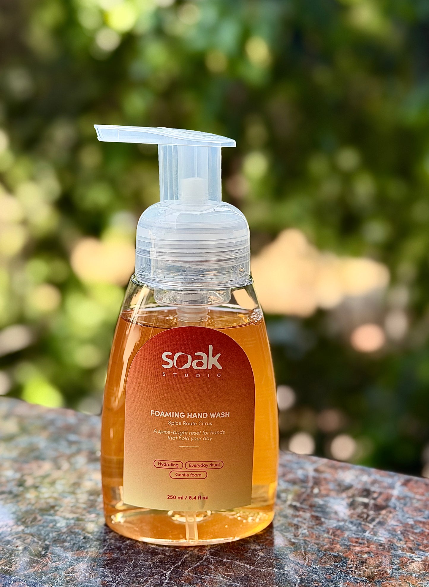 Soak Studio Spice Route Citrus Foaming hand wash bottle with a visible brand label on a blurred natural background