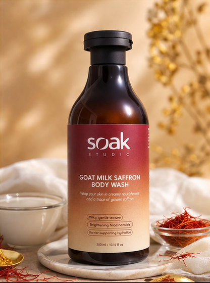 Bottle of Soak Studio Goat Milk Saffron Body Wash on a decorative background with saffron and milk.