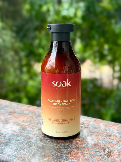 Bottle of Soak Goat Milk Saffron Body Wash on a stone surface with a blurred green background
